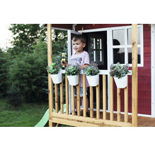 Hrací domček s chlapcom, kvetináče a hračky na verande v záhrade