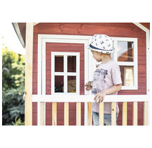 Dieťa pred dreveným hracím domčekom s oknom a plotom