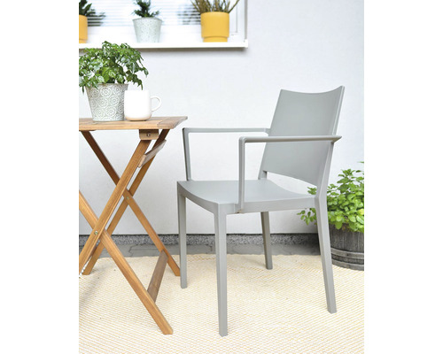 Sivá záhradná stolička s podrúčkami vedľa dreveného stola