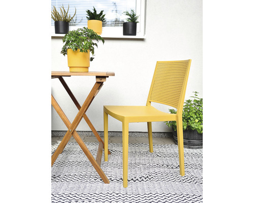 Scéna s dreveným záhradným stolom, žltou záhradnou stoličkou a vonkajším kobercom