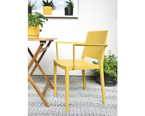 Žlté plastové kreslo na balkóne so stolom a rastlinami
