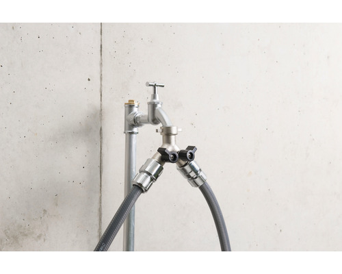 Vodovodný kohútik s dvoma prípojkami a hadicovými prípojkami pred betónovou stenou