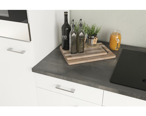 Kuchynské zátišie s doskami na krájanie, fľašami na olej, bylinkami a varnou doskou na pracovnej doske