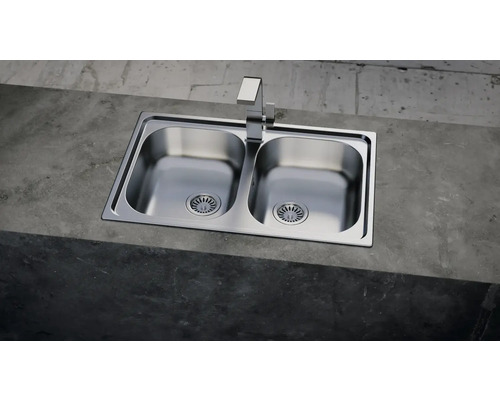 Nerezový dvojdrez s vodovodnou batériou na betónovom povrchu