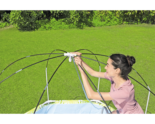 Žena stavia v záhrade bazénik s ochranou proti slnku.