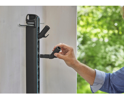 Držiak záhradného náradia na stenu s osobou pripevňujúcou hadicovú prípojku