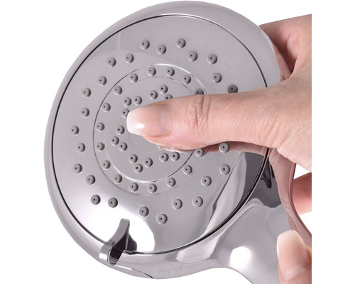 Ruka čistí trysky sprchovej hlavice.