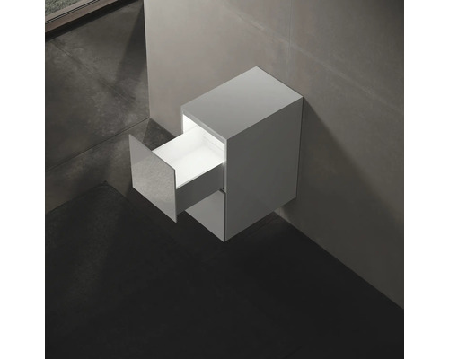 Závesná skrinka pod umývadlo s otvorenou zásuvkou v kúpeľni.