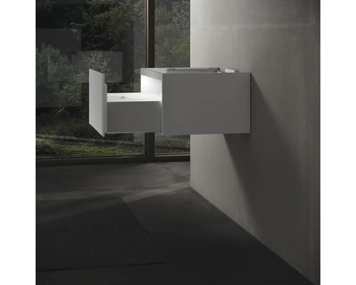 Biela skrinka pod umývadlo s otvorenou zásuvkou namontovaná na stene