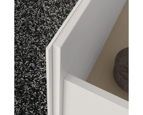 Detail bieleho kusu nábytku so zásuvkou a kobercom