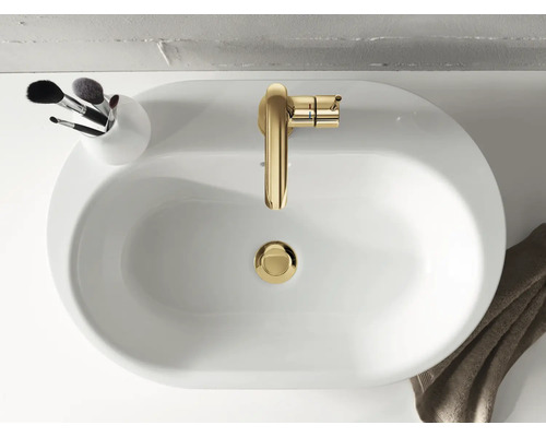 Pohľad zhora na biele umývadlo so zlatou batériou a nádobou so štetcami na make-up