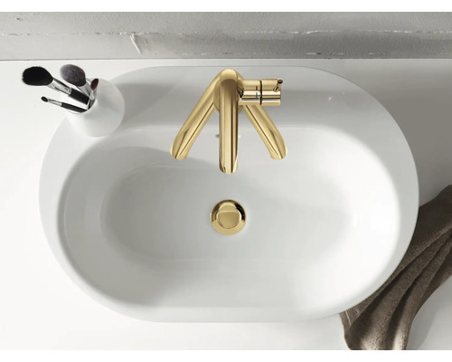 Pohľad zhora na umývadlo so zlatou batériou, držiakom s kozmetickými štetcami a uterákom