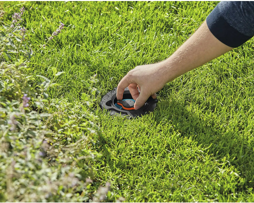 Osoba nastavuje zapustený zavlažovač trávnika v trávniku.