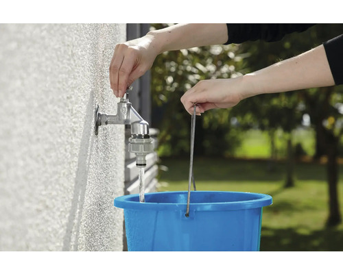 Vodovodný kohútik sa otvára na naplnenie modrého vedra