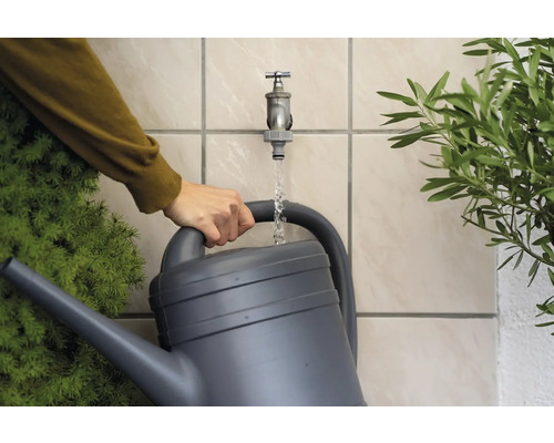 Zalievacia kanva sa plní vodou pod kohútikom na polievanie rastlín.