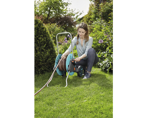 Žena používa vozík na záhradnú hadicu v záhrade.