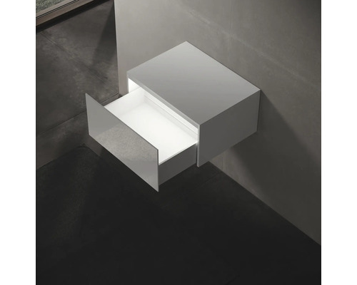 Závesná skrinka pod umývadlo s otvorenou zásuvkou v kúpeľni.