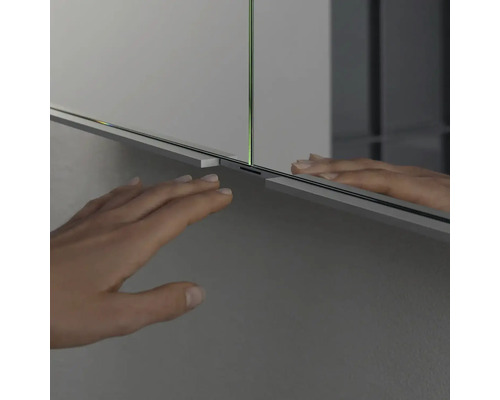 Detailný záber zrkadlovej skrinky s rukou v kúpeľni