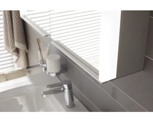 Detail kúpeľne s osvetlenou zrkadlovou skrinkou, umývadlom a vodovodnou batériou