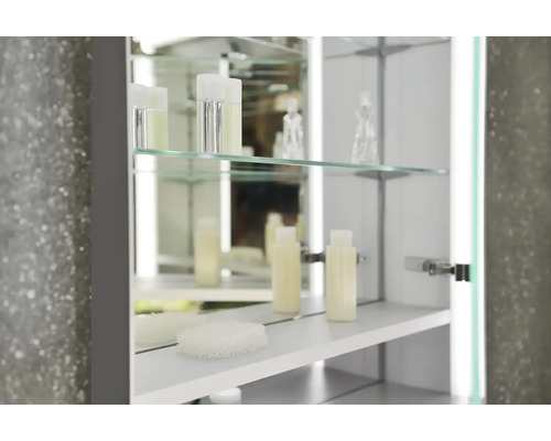 Otvorená zrkadlová skrinka so sklenenými policami a ošetrujúcimi produktmi