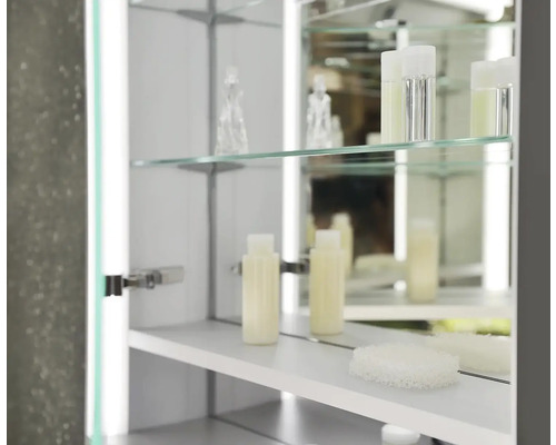 Otvorená zrkadlová skrinka so sklenenými policami a kúpeľňovými doplnkami