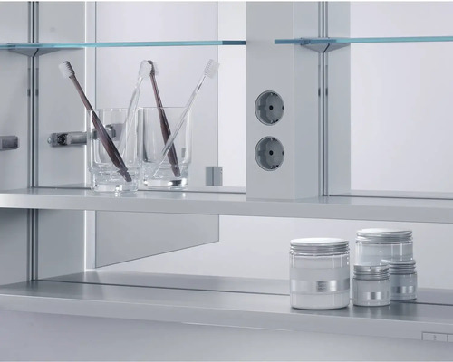 Kúpeľňová scéna s pohármi na zubné kefky, zubnými kefkami, zásuvkami a kozmetickými dózami v zrkadlovej skrinke