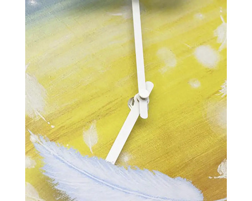 Detail nástenných hodín s dizajnom peria a bielymi ručičkami.