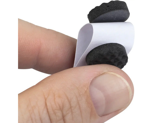 Dva klzáky na nábytok s papierovým prúžkom drží ruka.