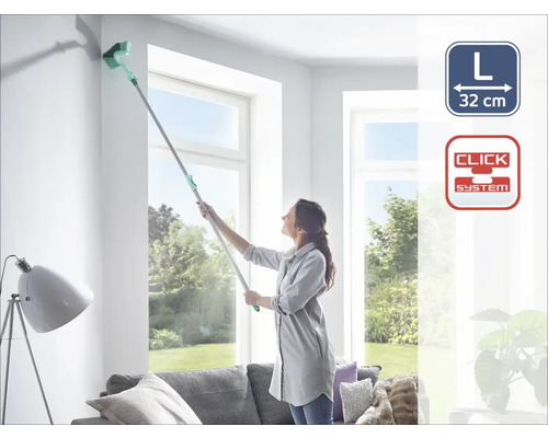 Žena čistí roh stropnou kefou na teleskopickej tyči v obývacej izbe