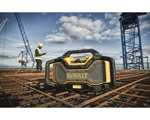 Stavebné rádio DeWalt na stavenisku so stavebným robotníkom a žeriavom v pozadí