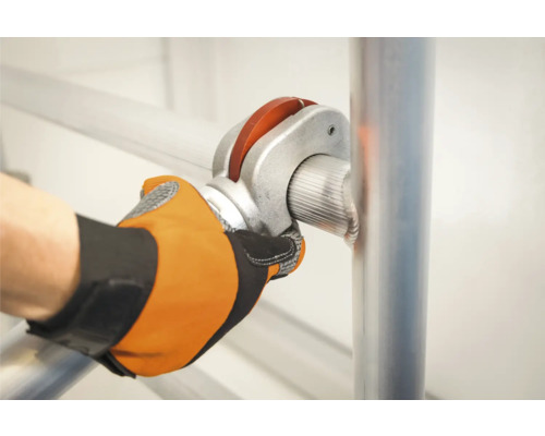 Osoba upevňuje rúrku lešenia pomocou rúrkového spoja