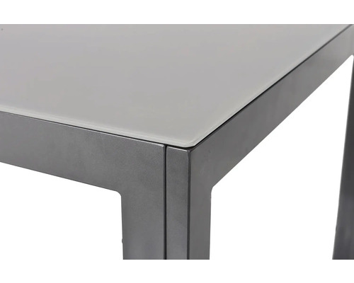 Detail stola so sklenenou doskou a kovovým rámom.