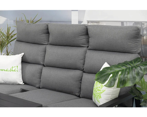 Detail šedej vonkajšej pohovky s vankúšmi a rastlinami