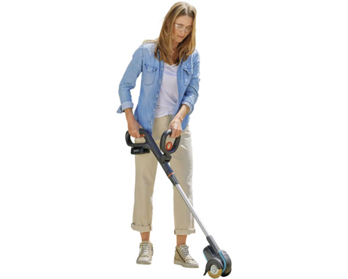 Žena používa akumulátorový čistič škár v záhrade.