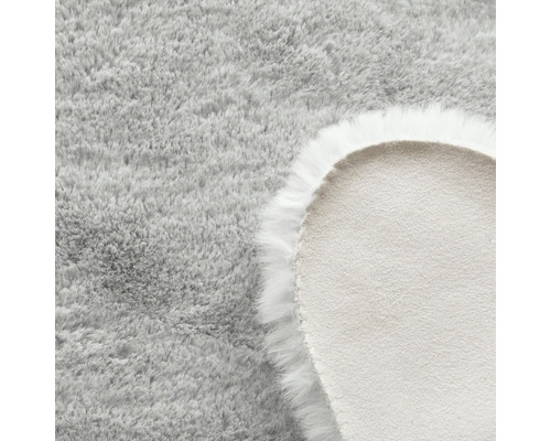 Detail okrúhleho svetlosivého koberca s dlhým vlasom