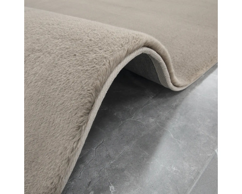 Detailný pohľad na béžový koberec s vysokým vlasom.