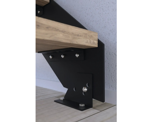 Detail upevnenia schodiska z čierneho kovu s dreveným schodom.