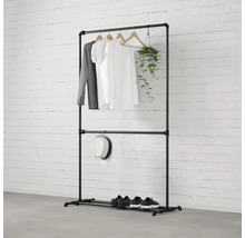 Čierny kovový vešiak na oblečenie s oblečením, klobúkom, topánkami a rastlinou