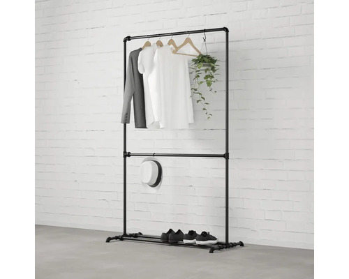 Čierny kovový vešiak na oblečenie s oblečením, klobúkom, topánkami a rastlinou