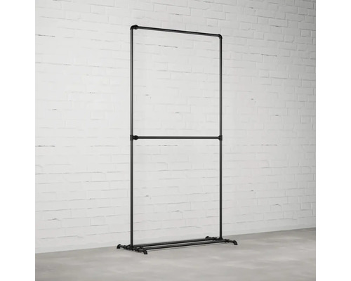 Stojan na šaty z rúrok v industriálnom dizajne pred tehlovou stenou