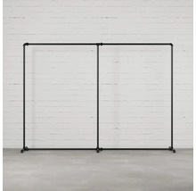 Dvojitý vešiak na šaty z rúrok pred tehlovou stenou