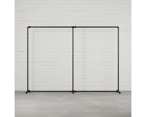 Dvojitý vešiak na šaty z rúrok pred tehlovou stenou