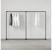 Čierny vešiak na oblečenie s oblečením visiacim pred tehlovou stenou