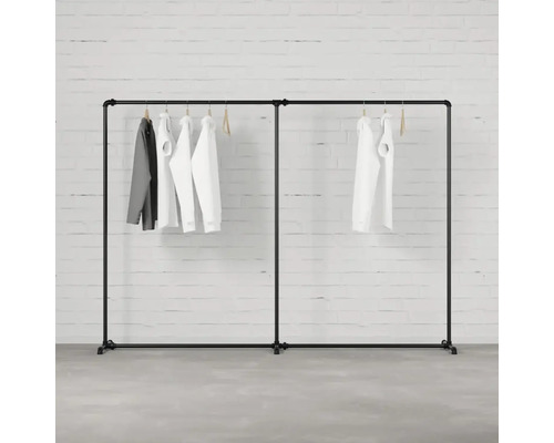 Čierny vešiak na oblečenie s oblečením visiacim pred tehlovou stenou