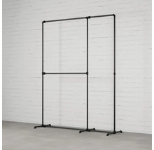 Vešiak na šaty z rúrok pred tehlovou stenou