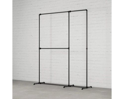 Vešiak na šaty z rúrok pred tehlovou stenou