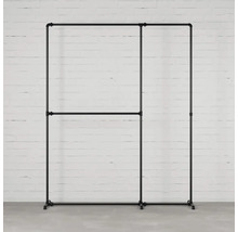 Stojan na oblečenie z kovových rúrok pred bielym tehlovým múrom