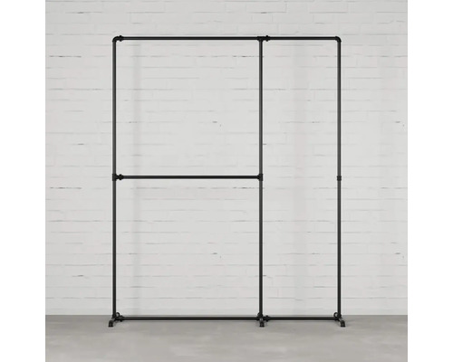 Stojan na oblečenie z kovových rúrok pred bielym tehlovým múrom