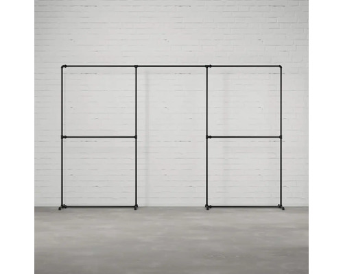 Čierny, modulárny šatník so stojanom na odevy z kovových rúrok na pozadí bielej tehlovej steny.