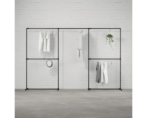 Čierny modulárny šatníkový systém s oblečením a dekoráciou pred tehlovou stenou